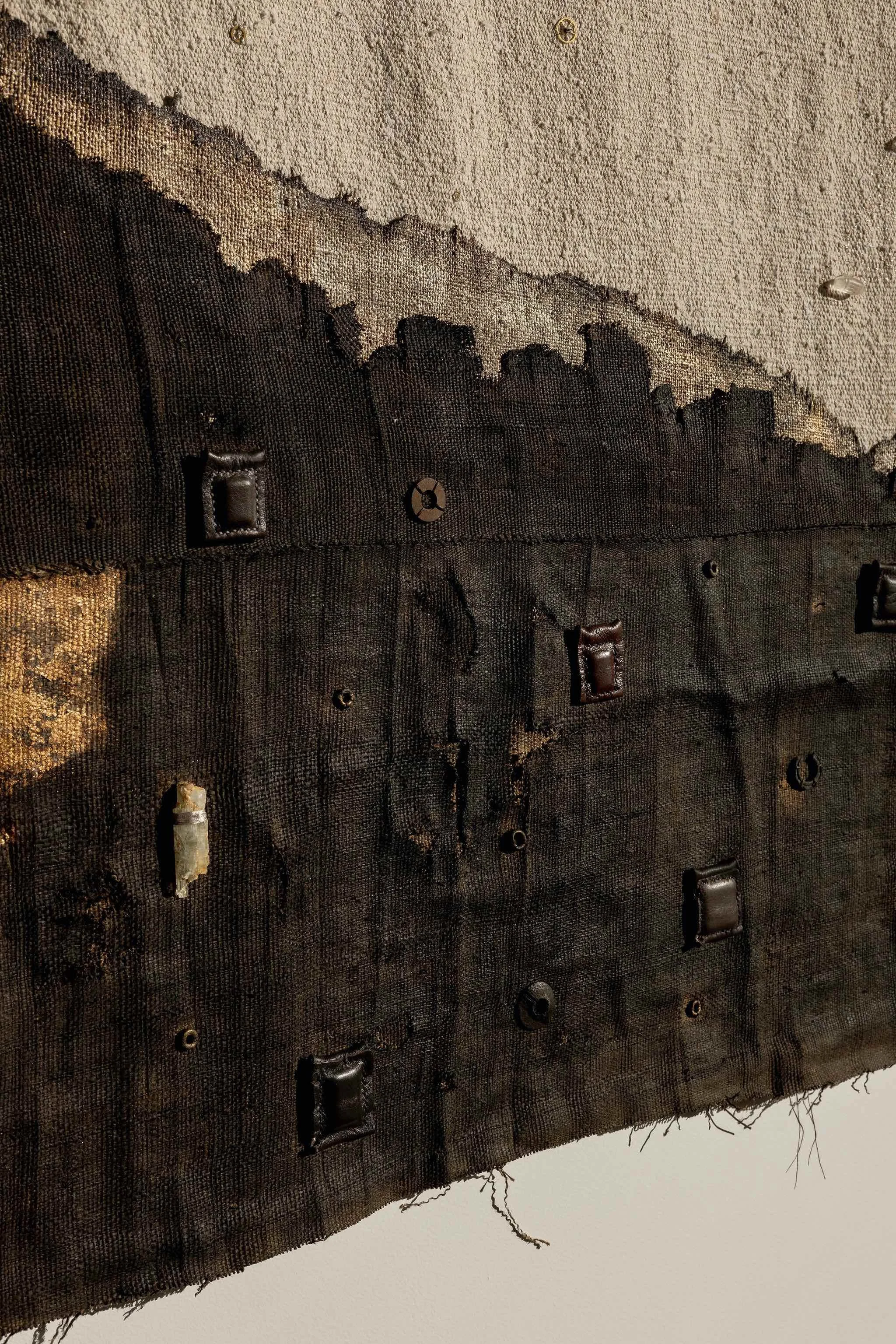 Detail of the charred surface and stitched gold leaf.
