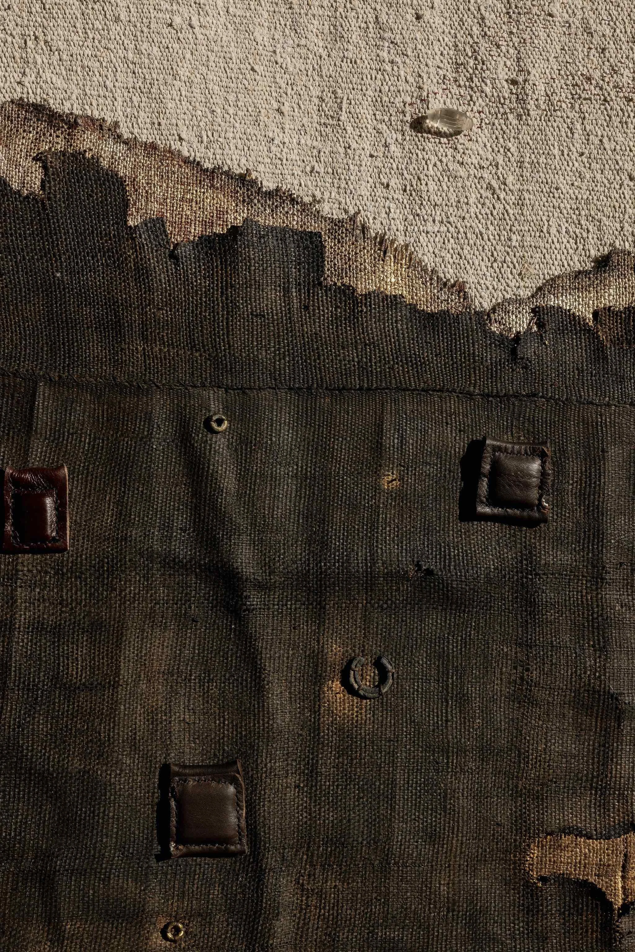 Detail of found objects and small leather packets worked into the surface.