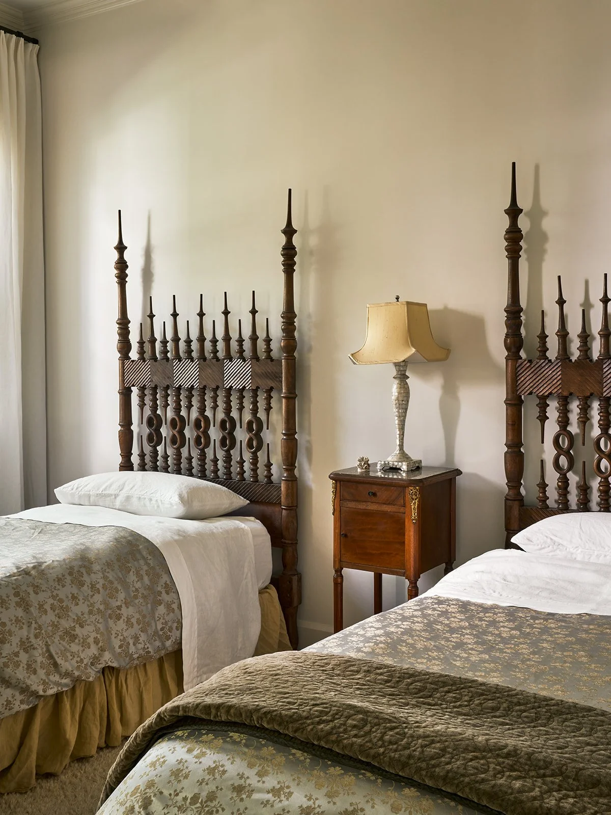 Guest bedroom featuring twin vintage Portuguese wood beds, a central antique nightstand, and layered Bella Notte linens.