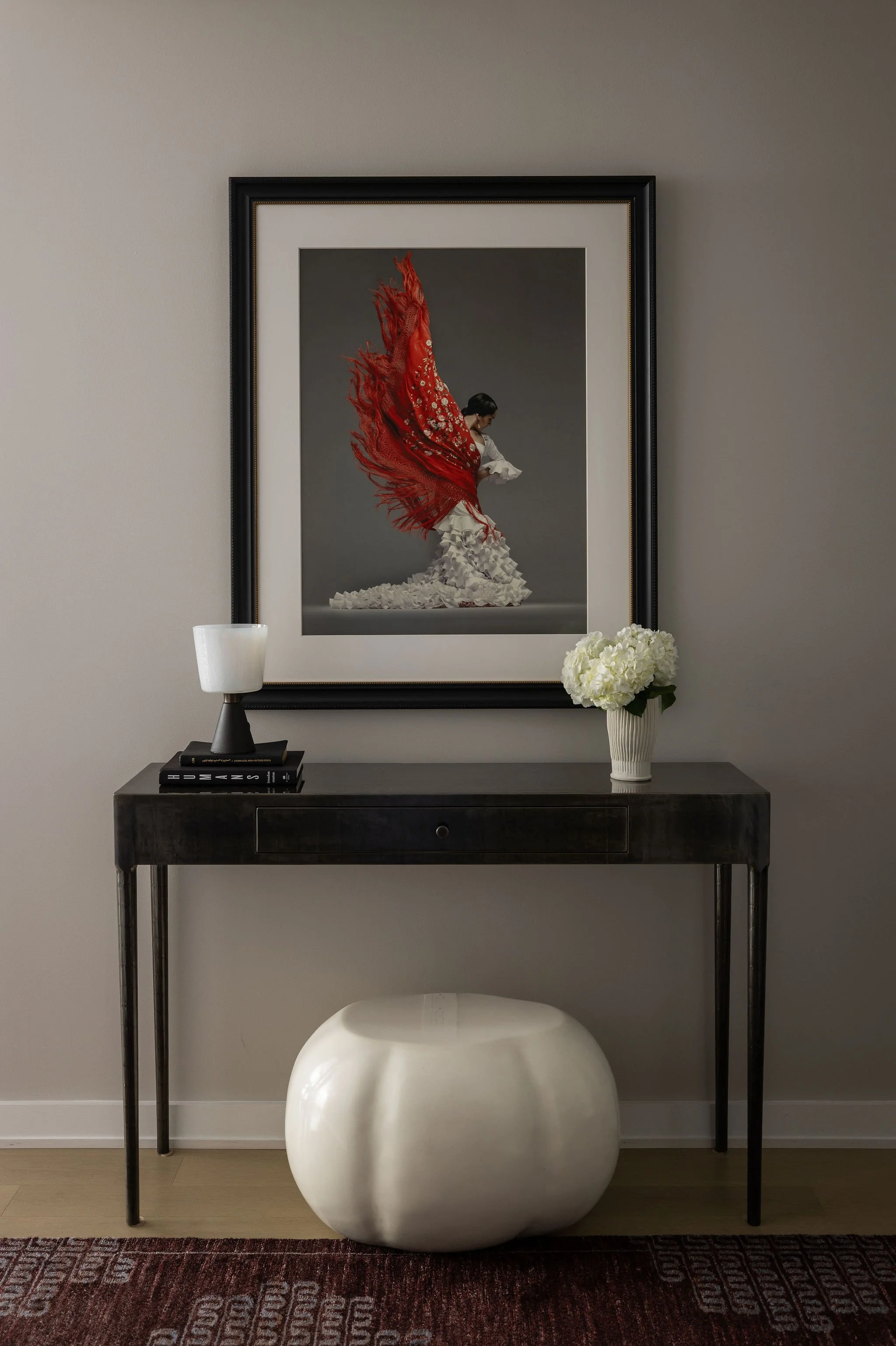 Foyer of a Georgetown condo, featuring a dramatic flamenco dancer artwork displayed above a finely crafted steel console, creating a bold and elegant first impression.