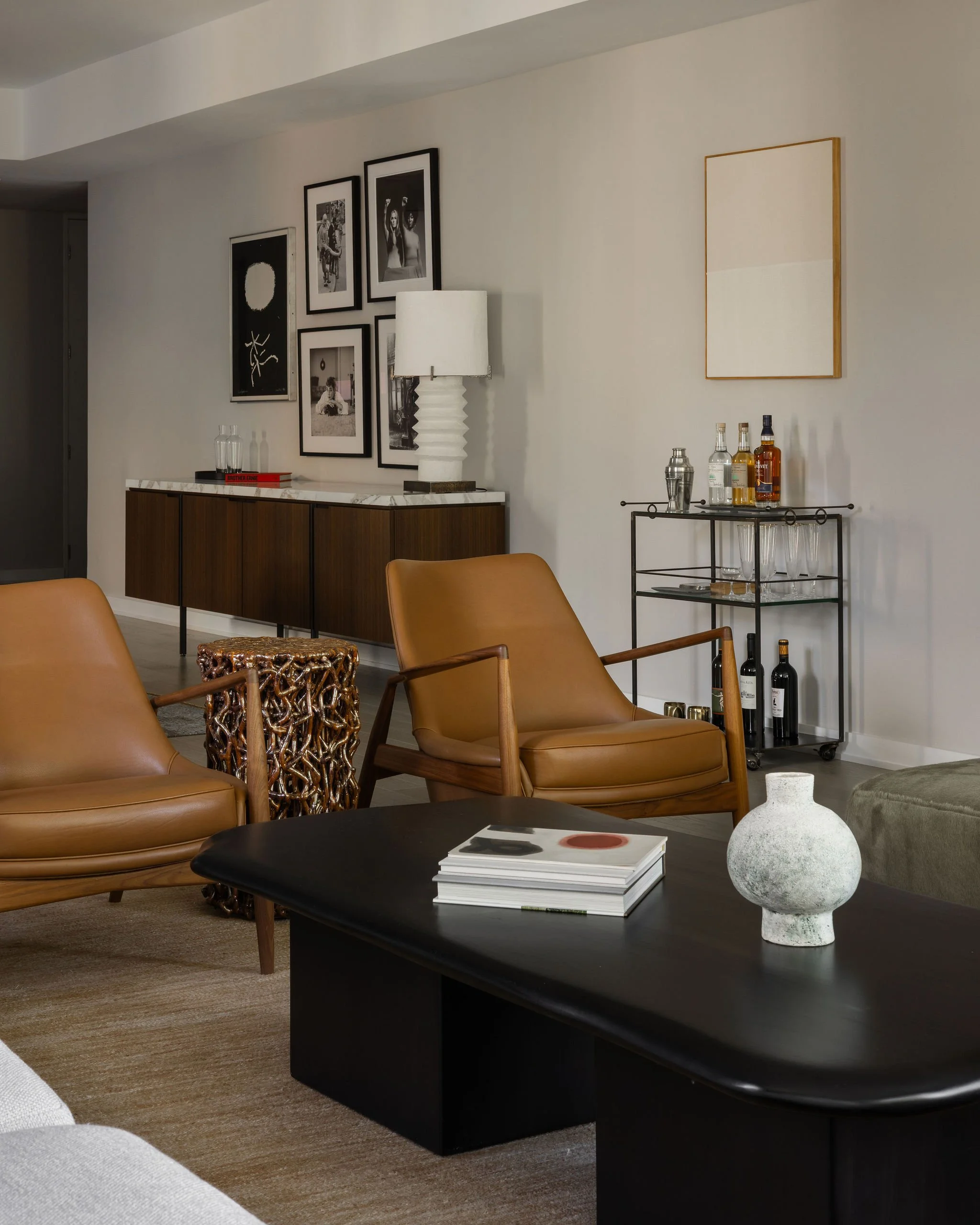 View from living room to dining room in a Georgetown condo, featuring a styled bar cart with artwork by Ethan Cook and a salon-style art installation reflecting the client’s personal collection.