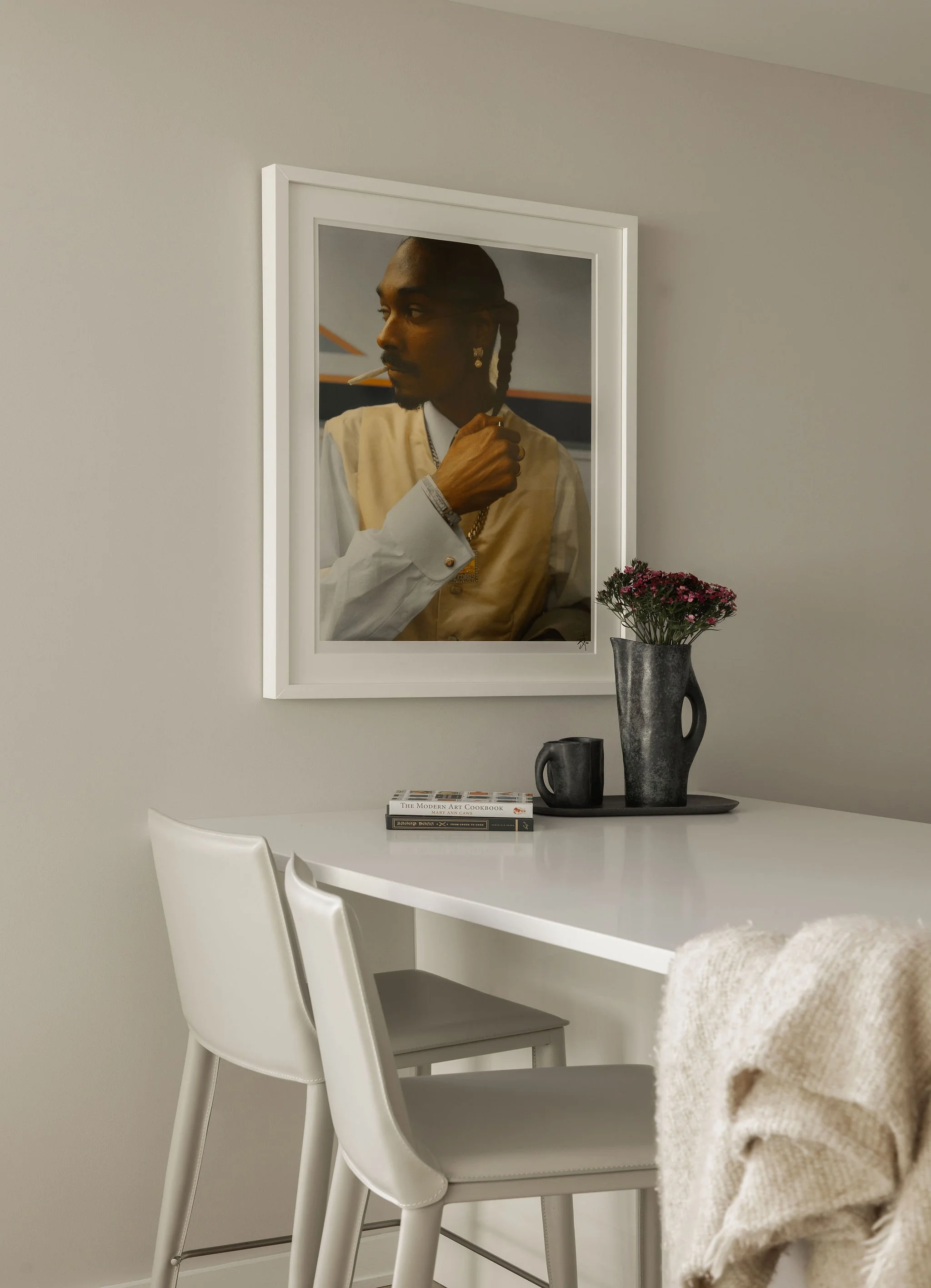 Georgetown condo kitchen with white countertops, leather barstools, and a framed portrait photograph of Snoop Dogg.